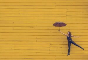 女性　傘　黄色い壁